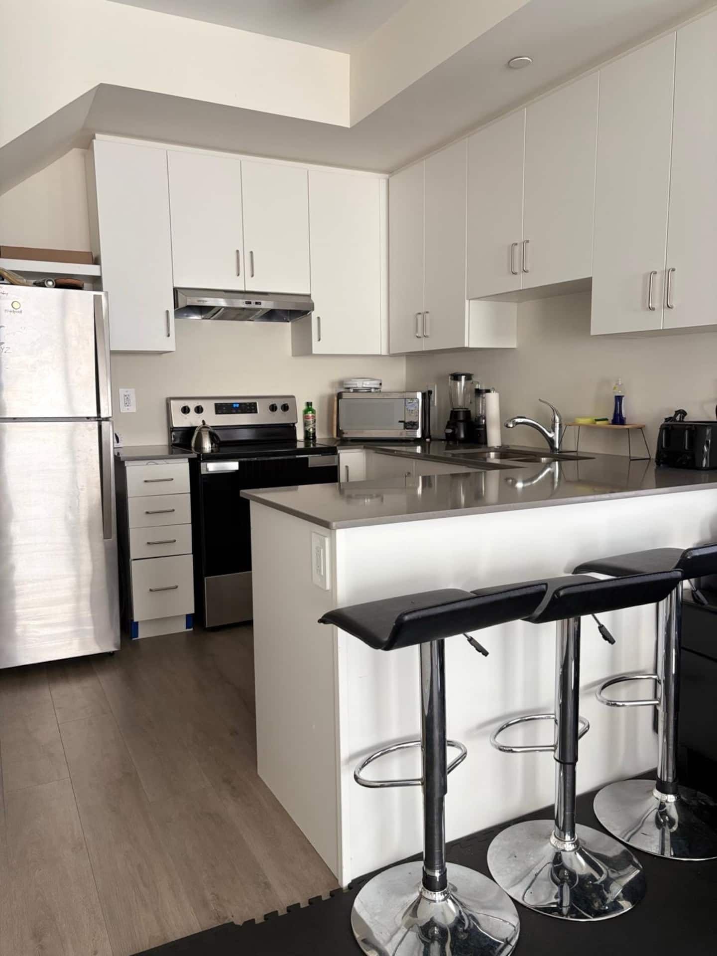 Full kitchen with white cabinets, appliances and breakfast bar